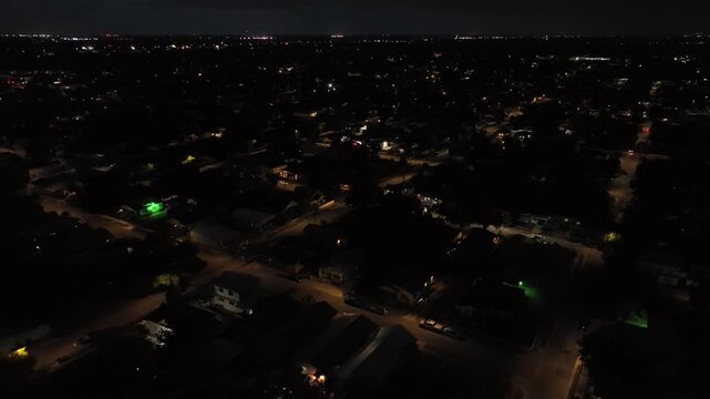 Tampa neighborhood at night. Aerial backwards shot. Housing area and homes in suburb district. Driving cars on street in quiet area. Top down. Florida, United States.