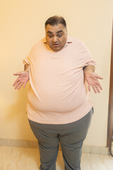 Unhappy overweight indian man looking belly fat with surprised expression. Plus size guy feels disgusted with his body shape. obesity and Lose weight concept.