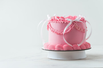 Delicate lambeth style birthday cake with pink cream cheese frosting decorated with cream tracery and happy birthday text on top. White background