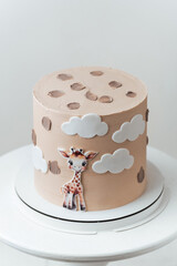 Cute African style birthday cake with beige chocolate icing decorated with edible giraffe on the white background.