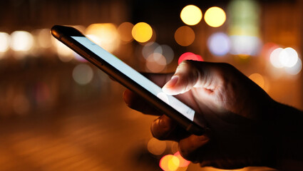 Person using smartphone at night with bokeh lights hand finger