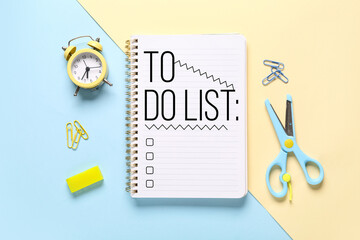 Notebook with blank to-do list, alarm clock and stationery on color background