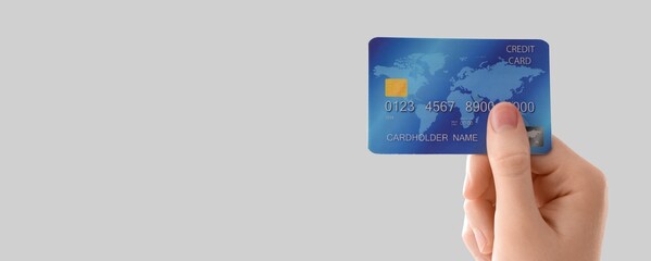 Hand holding credit card on grey background with space for text, closeup