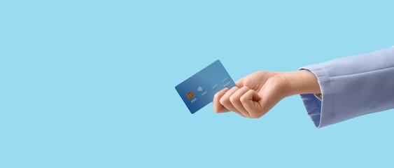Hand holding credit card on light blue background with space for text