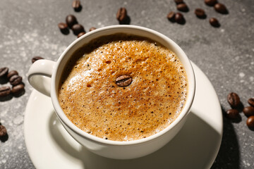 Cup of delicious espresso and coffee beans on grey background, closeup