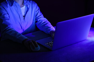 Female programmer typing on laptop keyboard at night in office, closeup