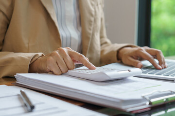 Business woman calculating financial statement on calculator income tax online return and payment.