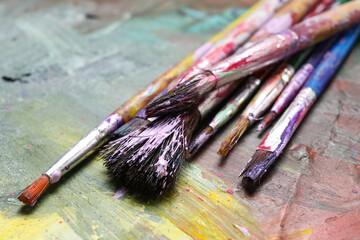 Dirty paint brushes on colorful background