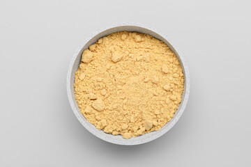 Bowl with ginger powder on grey background