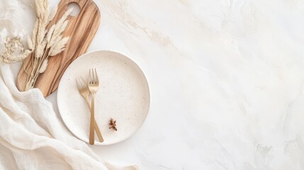A set of gold forks on a speckled white plate with dried grasses and a wooden cutting board.