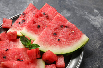 Plate with pieces of ripe watermelon on dark background, closeup
