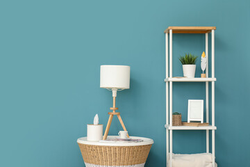 Lamp on small table and shelving unit near blue wall