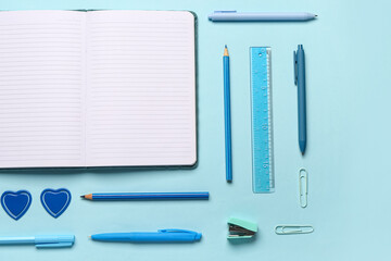Notebook with different stationery supplies on blue background