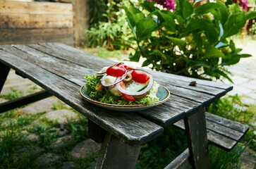 Plate of salad sits on a wooden picnic table in a garden