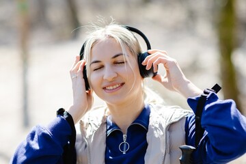 Smiling blonde woman wearing headphones enjoying music outdoors