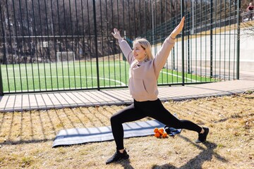 Young woman stretching legs practicing yoga asana outdoors in the park