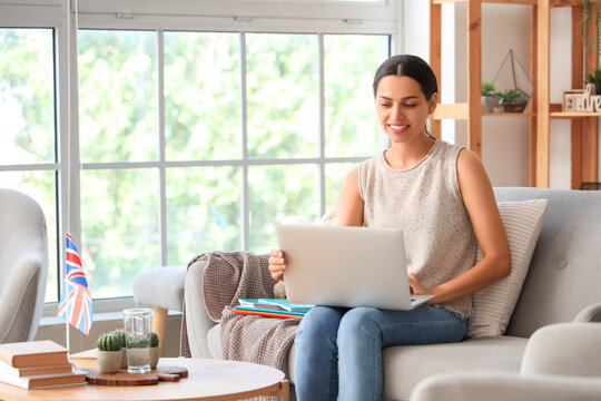 Young woman with laptop learning English language online at home