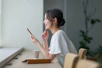  カフェでスマホを使う女性 © naka