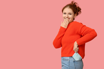 Beautiful young woman with menstrual pad on pink background