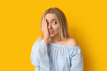 Embarrassed young woman on yellow background