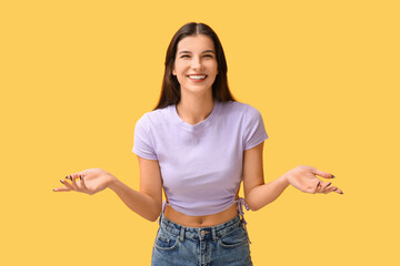 Beautiful happy young woman laughing on yellow background