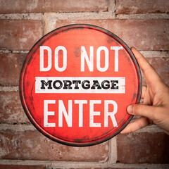 Red Do Not Enter Mortgage Sign Held by Hand Against Brick Wall Background for Financial Concept