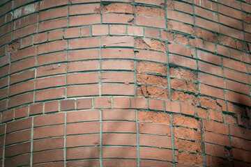 Weathered Brick Wall with Cracks and Uneven Surface Texture in Harsh Sunlight