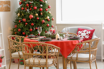 Stylish interior of festive living room with Christmas tree and served dining table