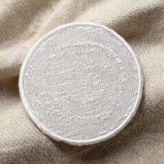 Round White Embroidered Patch on Beige Fabric with Soft Textured Sheen  Closeup with Frayed Edges on Blurred Background