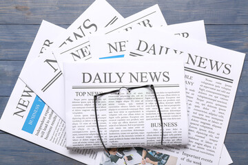 Newspapers with glasses on blue wooden background