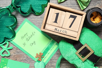 Leprechaun hat with calendar, eyeglasses and festive postcard on grey wooden background. St....