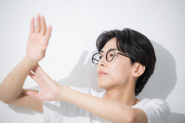 日焼け止めを塗る眼鏡の男性　腕に日焼け止めなどを塗る　夏の暑さ対策