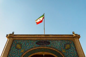 Waving Flag of Iran in Blue Sky. symbol of the state on wavy cotton fabric.