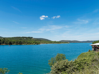 Lac de Sainte-Croix au pied des gorges du Verdon. Vue sur l'embouchure du ravin de la Combe face au village de Bauduen adossé à la falaise rocheuse
