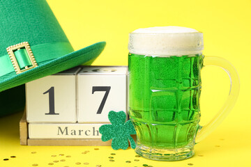 Cube calendar with date 17 MARCH, glass of beer and leprechaun hat on yellow background. St....
