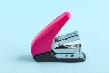 Pink stapler on blue background