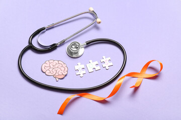 Paper brain with puzzle pieces, stethoscope and orange ribbon on lilac background. Multiple...