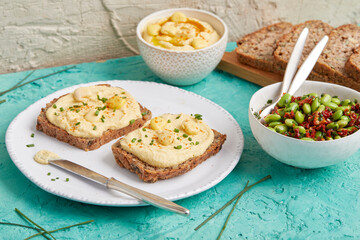 Hummus on bread slices with edamame salad in a bowl