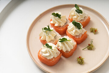 Homemade rolls with red fish and cottage cheese on a plate on a white background