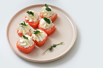 Homemade rolls with red fish and cottage cheese on a plate on a white background