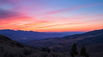 Vibrant sunset paints the sky with hues of pink, orange, and purple, casting a warm glow over a vast mountainous landscape