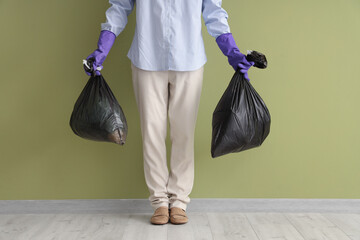 Woman with garbage bags near green wall