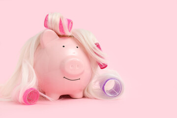 Piggy bank in wig with hair curlers on pink background