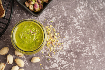Jar of pistachio paste on grey grunge background