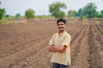 young indian farmer standing at agricultural field