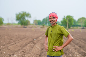 young indian farmer standing at agricultural field
