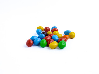 Colorful candy-coated chocolate pieces scattered on a white background
