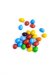 Colorful candy-coated chocolate pieces scattered on a white background