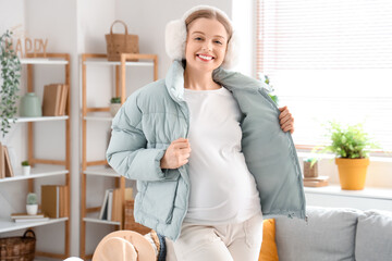 Young pregnant woman in warm clothes ready for vacation at home