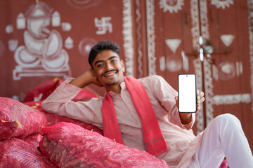 young indian farmer showing smartphone screen